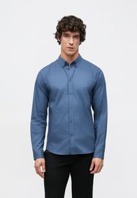 Overhemd met knopen in diepblauwe stof met een gladde textuur, voorzien van een puntige kraag en lange mouwen, gecombineerd met een donkere broek.