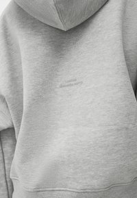 Sudadera gris con capucha, que presenta una tela texturizada y el texto bordado "Puedo ser dramático, lo siento" en la parte de atrás.