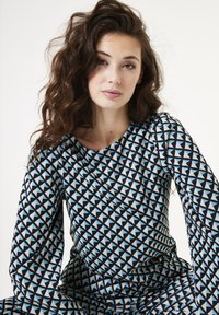 Zwart en lichtblauw patroonjurk met driehoekige geometrische ontwerpen, ronde halslijn en lange puff sleeves. Gladde textuur.