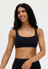 Svart cropped bralette med breda band och fyrkantig halsringning. Slät textur, minimalistisk design och ingen synlig hårdvara eller mönster.