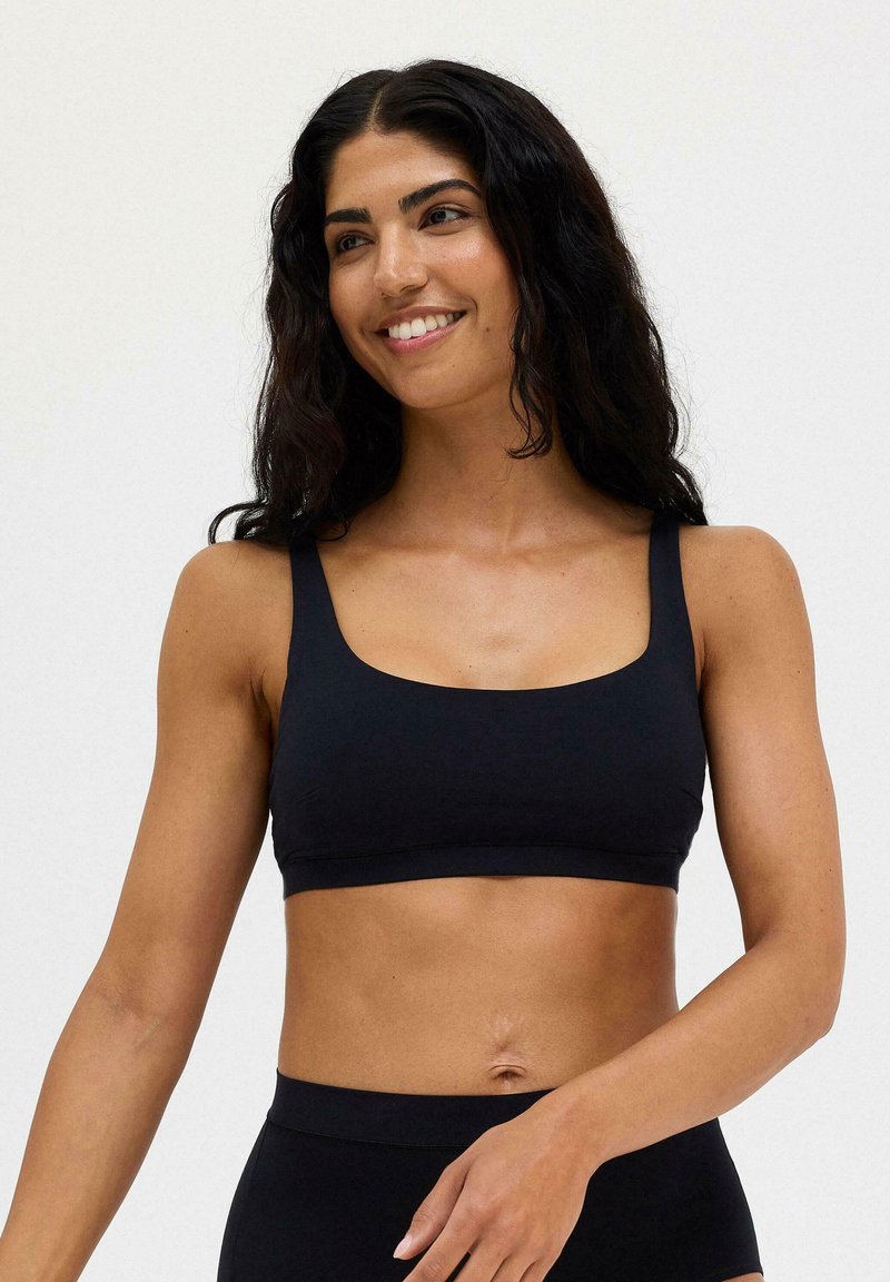 Svart cropped bralette med breda band och fyrkantig halsringning. Slät textur, minimalistisk design och ingen synlig hårdvara eller mönster.