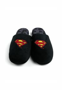 Pantofole in camoscio nero con un logo di Superman ricamato in rosso e giallo su ciascuna. L'interno presenta un design a motivo del logo.
