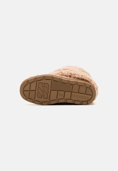 Harmaa, pörröinen liukkaasti menevä kenkä, jossa on teksturoitu yläpinta ja kumipohja, jossa on syvät urat ja merkkilogo.