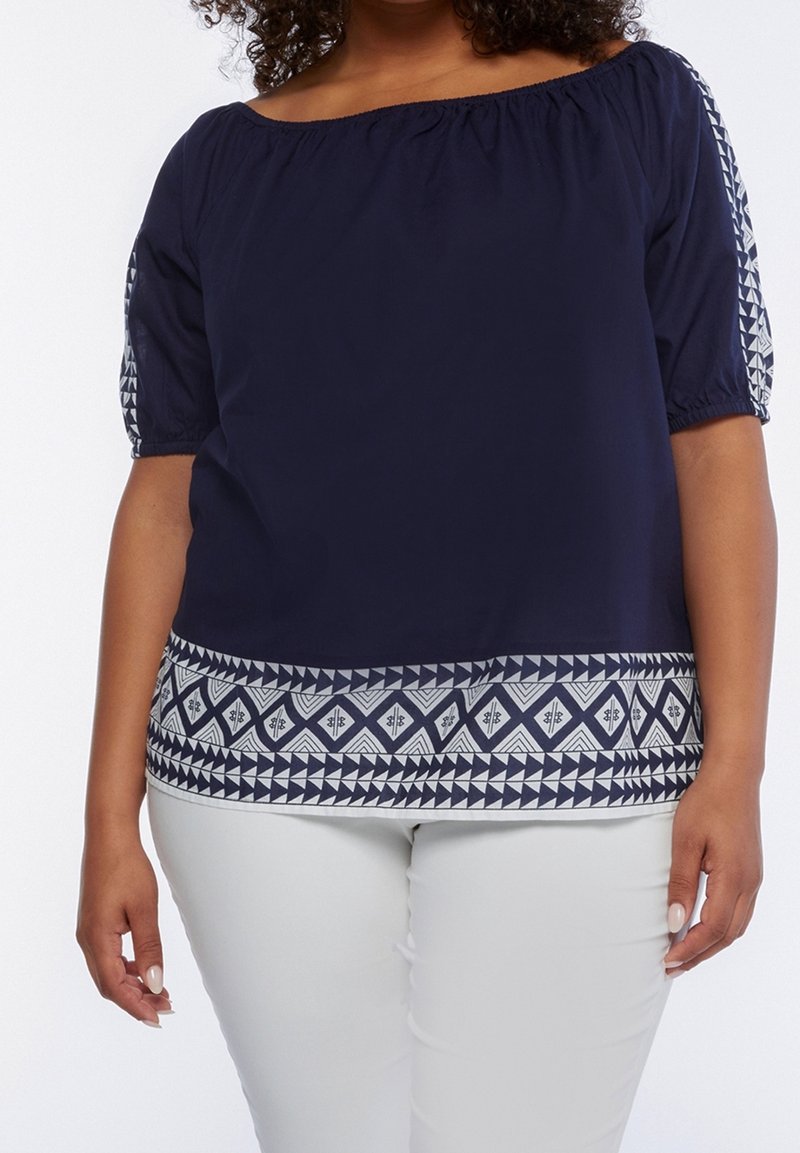 Navy blue off-shoulder blouse with elastic neckline and puffed sleeves. Features white geometric patterned trim at the hem and sleeves.