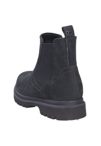 Stivale alla caviglia in suede nero con pannelli laterali elasticizzati, tacco rinforzato e suola in gomma texturizzata. Presenta cuciture minime e una linguetta per una facile calzata.