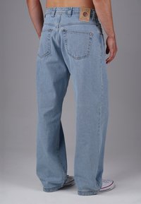 Hellblaue Denim-Jeans mit lockerer Passform, ausgestattet mit einem Patch am hinteren Bund und zwei hinteren Taschen mit sichtbaren Nähten.