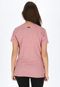 T-shirt rosa a maniche corte realizzato in tessuto morbido, con collo rotondo e una piccola etichetta nera sul retro, vicino al collo.
