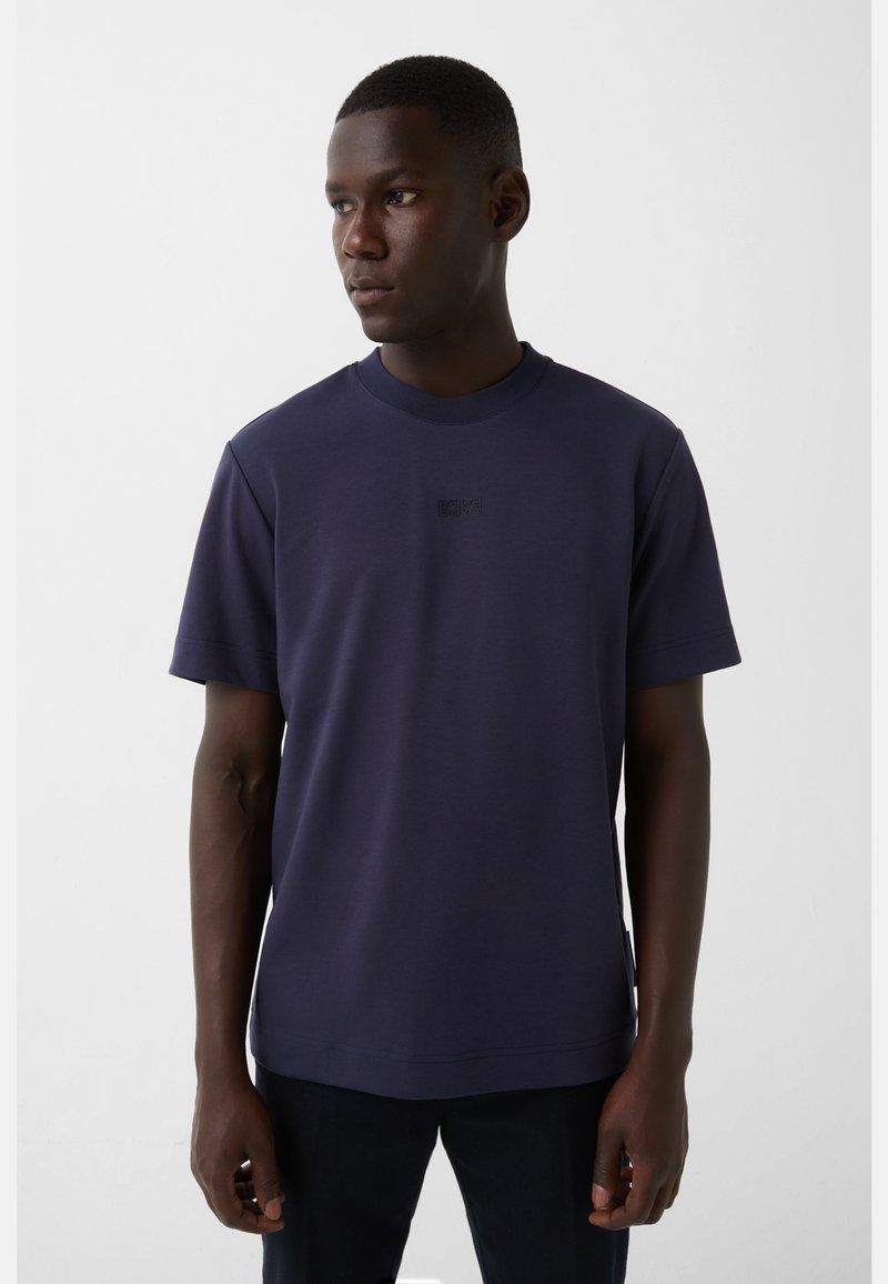 Marineblå crew-neck t-shirt i glat bomuldsblanding med korte ærmer og et diskret logo på brystet, tætsiddende design.