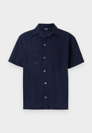 Tumesinine lühikeste varrukatega särk, millel on broderie lilled, nupuga ees ja klassikaline krae. Valmistatud kergetest kangastest.