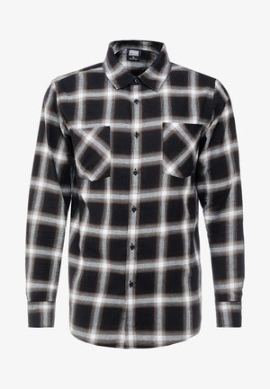 Pitkähihainen ruutupaita mustassa, valkoisessa ja ruskeassa. Varustettu nappikauluksella ja kahdella rintataskulla, joissa on napilliset sulkut.