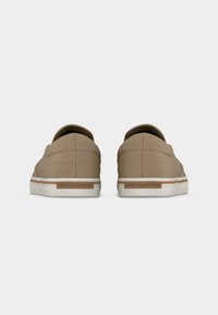 Paire de baskets casual beige à enfiler avec semelles blanches, vue de dos, montrant le nom de la marque sur la languette du talon.