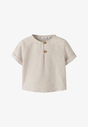 Chemise beige à manches courtes pour tout-petit, avec encolure ronde, deux boutons en bois sur la patte de boutonnage avant et manches retroussées.