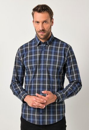 Camisa de botones con un patrón de cuadros en azul marino, azul y blanco. Fabricada con una tela de textura suave, de mangas largas y con cuello.