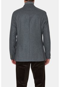 Blazer in lana grigia con colletto a revers, spacco singolo e polsini con bottoni, abbinato a pantaloni di velluto a coste marroni.