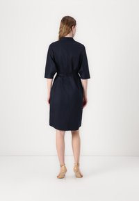Navy blue dress with a collared neckline, short sleeves, and a tied waist. Smooth texture, knee-length, simple design, and no visible patterns.