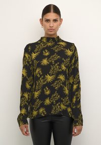 Maglietta nera a maniche lunghe con colletto alto, caratterizzata da un motivo floreale giallo. Tessuto liscio; vestibilità comoda, orlo leggermente più lungo sul retro.