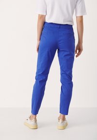 Klär blå byxor med slim fit, i bomullsmaterial och bakfickor. Avsmalnande ben med en lätt uppvikt nederkant. Kombinerat med ljusa skor.