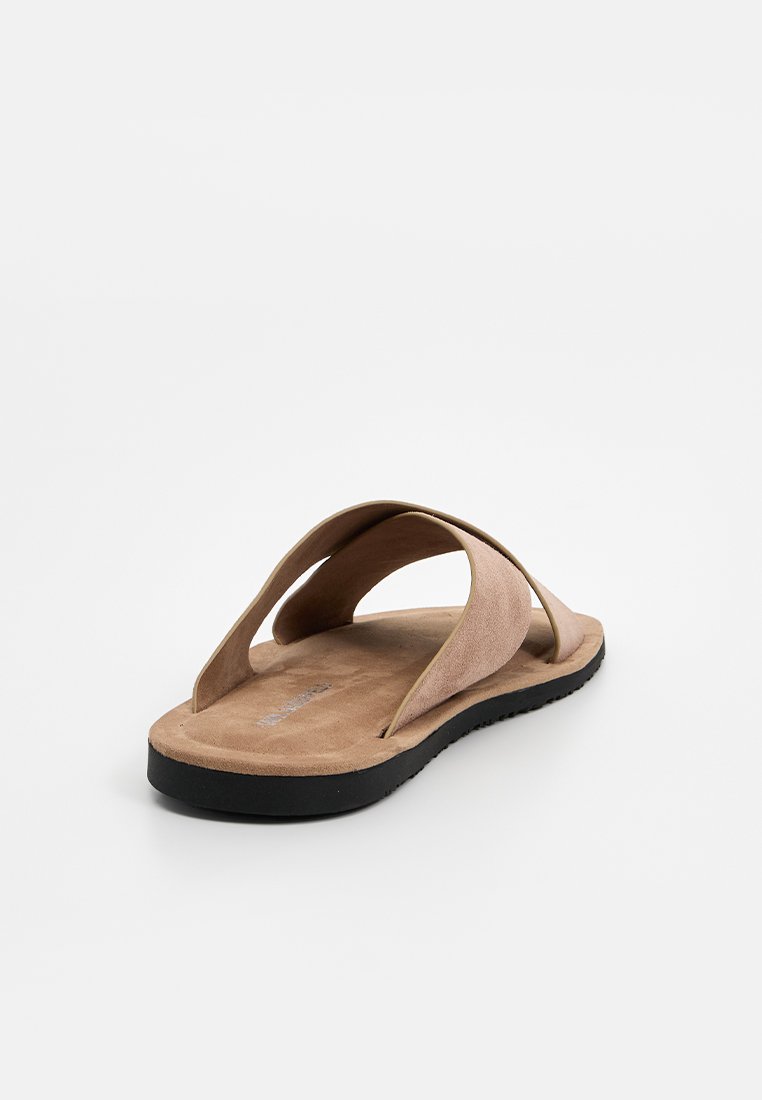 Braune Wildleder-Sandale mit zwei breiten Riemen, flacher schwarzer Gummisohle und strukturiertem Fußbett. Minimalistisches Design mit offener Ferse.