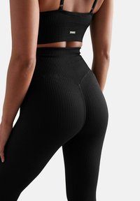 Set di abbigliamento attivo nero a coste composto da un top corto e leggings a vita alta, che mette in risalto il design aderente e il tessuto testurizzato.