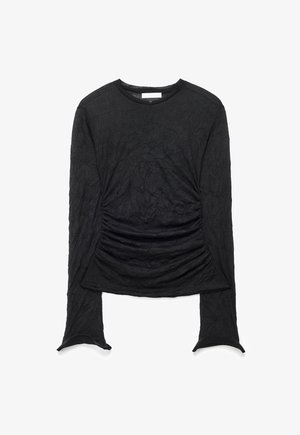 Black long-sleeve crew neck top with ruched detailing at the waist and subtle textured pattern throughout the fabric.