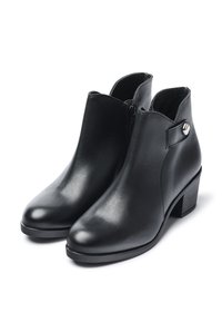 Botas de cuero negras hasta el tobillo con una textura suave, cremallera lateral y un acento de botón plateado. Tacón cuadrado para mayor estabilidad.