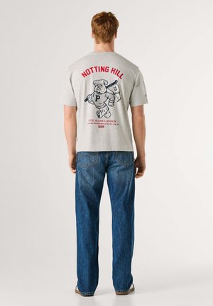 T-shirt gris en coton avec un graphisme d'un ours tenant une batte au dos, avec un texte rouge "NOTTING HILL" et "PEPE JEANS LONDON." Jean bleu.