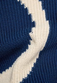 Strickpullover mit einem Farbschema in Marineblau und Creme, mit einem strukturierten Muster und diagonalen Streifen auf dem Stoff.