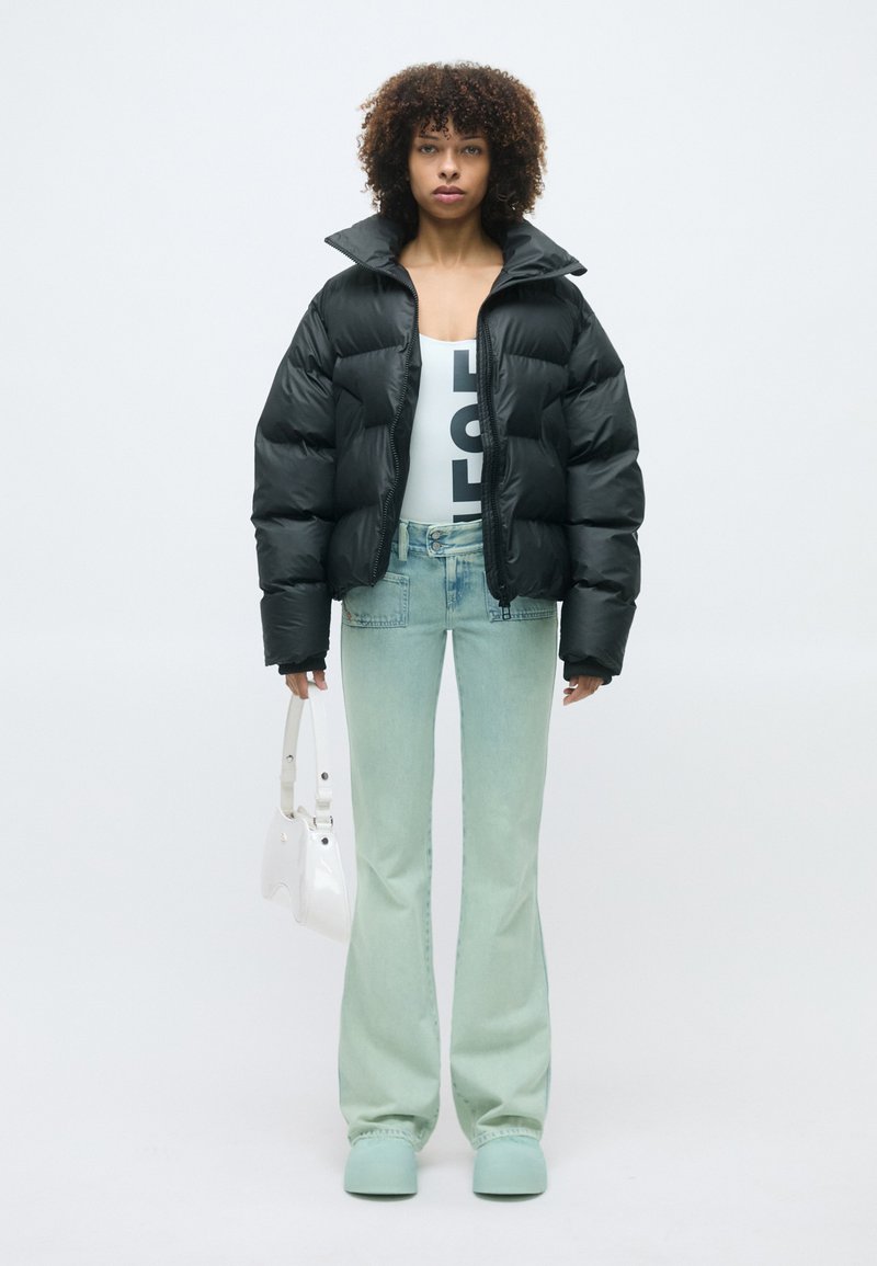 Sort pufferjakke, hvid grafisk bodysuit, lyseblå flared jeans, mintfarvede klip-klapper og hvid håndtaske. Glatte teksturer og livlige farver.