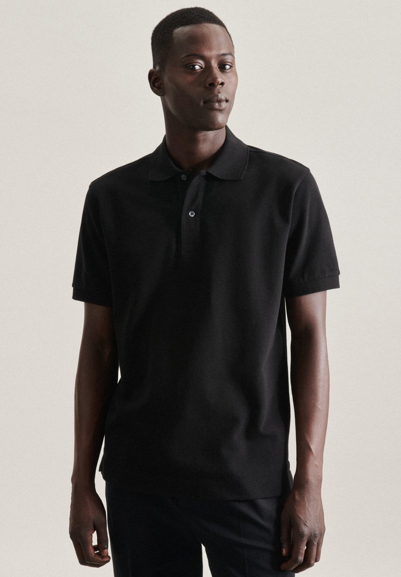 Polo nero realizzato in cotone con colletto classico, maniche corte e pattina con due bottoni. Texture morbida con una forma aderente.