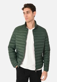 Giacca a vento verde con design a righe orizzontali, colletto alto, zip frontale e tasche laterali. Tessuto leggero, texture liscia.