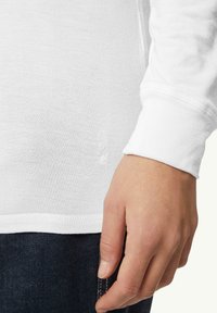 Biała koszula z długim rękawem z ribbowanym mankietem. Miękka, lekka tkanina. Posiada subtelne logo na dolnym brzegu oraz prosty krój.
