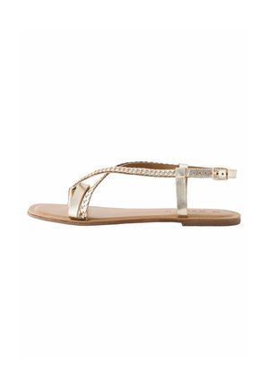 Platte sandalen met een metallic gouden afwerking, voorzien van gevlochten banden en een gespsluiting, rustend op een tankleurige zool. Eenvoudig en minimalistisch ontwerp.