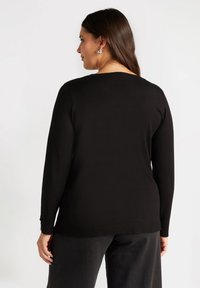 Suéter negro de manga larga con cuello redondo y dobladillo acanalado, que presenta acentos de botones en los puños, fabricado con una suave tela texturizada.