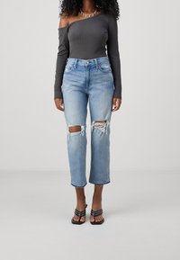 Šedý body bez ramínek spárovaný s světle modrými roztrhanými džíny s výřezem na kolenou, mírně třepenými lemy a černými sandály na řemínky.