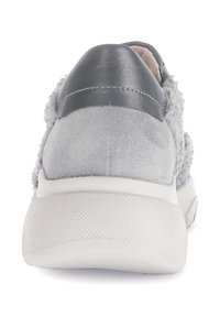 Grijze sneaker met een suède bovenwerk, zachte textuurelementen en een gladde leren hiel. De witte rubberen zool heeft een gestructureerd patroon voor grip.