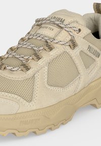 Μπεζ ορειβατικό παπούτσι Palladium Gore-Tex με πλέγμα, επενδύσεις από σουέτ, κορδόνια με σχέδια και στιβαρή σόλα για εξωτερική χρήση.