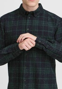 Cămașă cu mânecă lungă, în carouri verzi și bleumarin, cu guler button-down, având nasturi, textură presărată și un croi lejer.