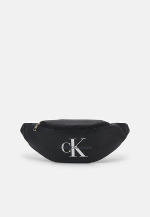 Sac banane noir Calvin Klein Jeans avec fermeture éclair argentée et grand logo blanc CK sur le devant.