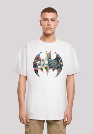 Hvit bomulls t-skjorte med et stort svart Batman-logo fylt med fargerike tegneseriepaneler. Løs passform med korte ermer.