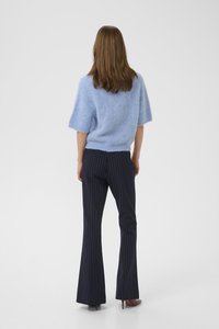 Light blue, fluffy knit short-sleeve sweater paired with dark blue pinstriped flared trousers and high-heeled shoes.