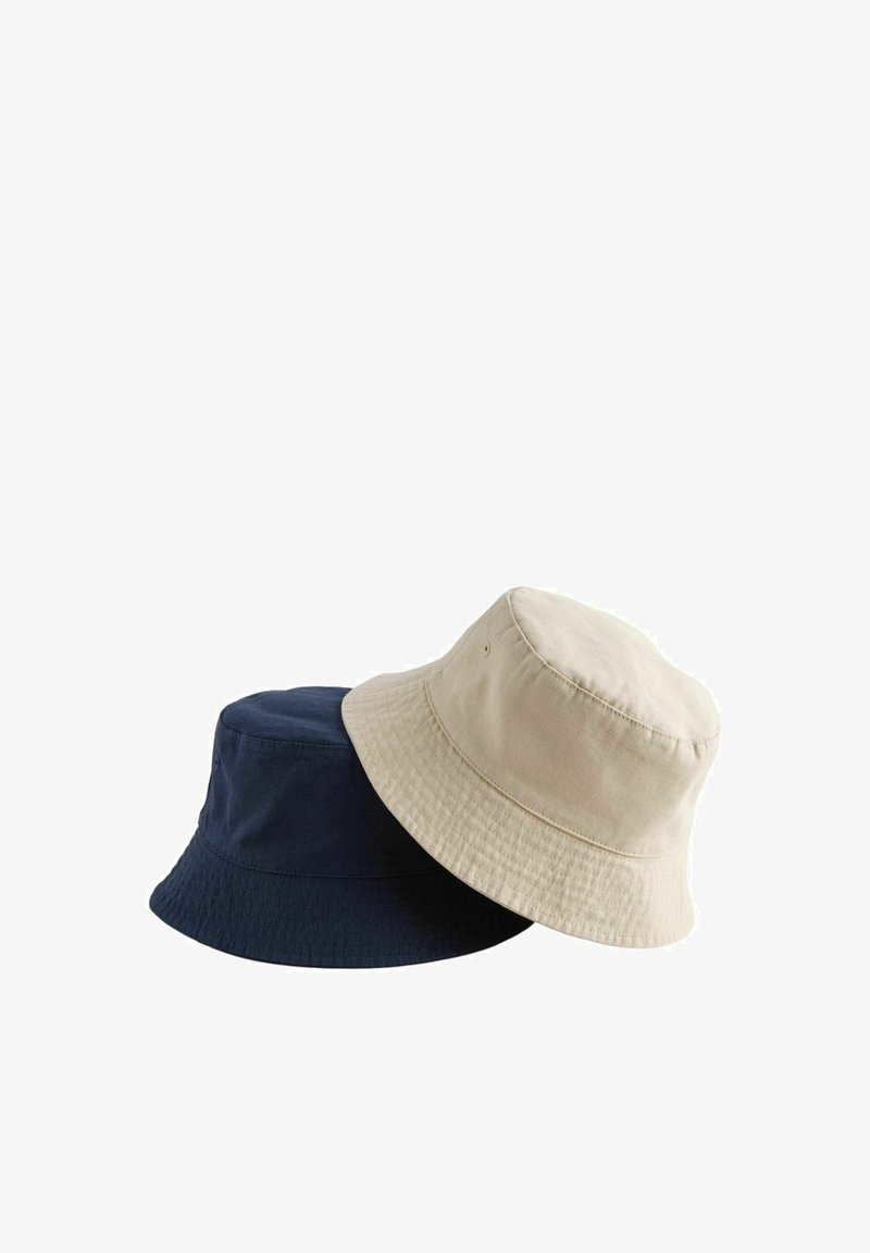 Chapeaux seau unis beige et bleu marine en coton empilés sur un fond blanc, montrant la texture douce du tissu et les bords cousus.