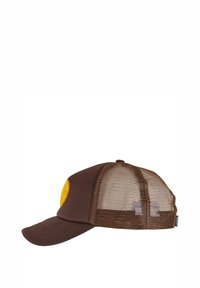 Bruine trucker pet met een gele ronde patch aan de voorkant, met een zachte stoffen voorkant en een gaasachterkant voor ventilatie.