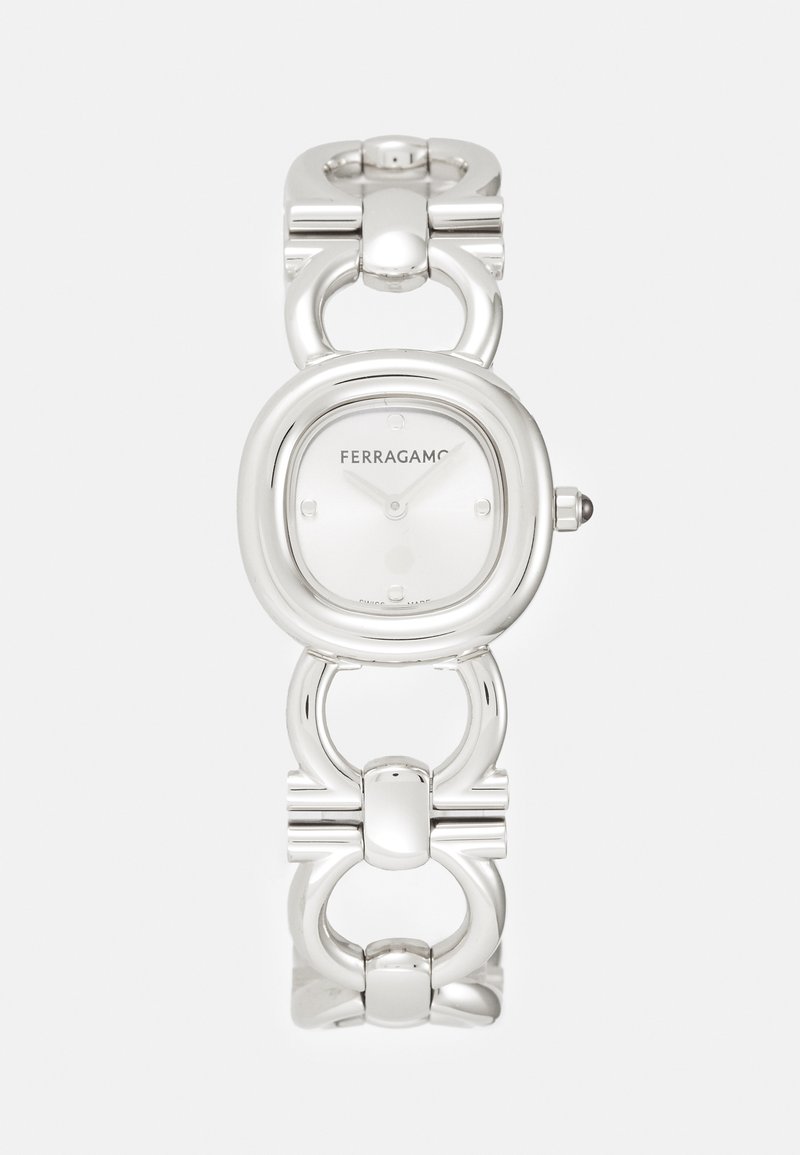 Hõbedatooniline kell ümarate ristküliku kujulise näoga, minimalistlik valge kellaplaat ja lingitud ketti käevõru, millel on poleeritud aktsendid.