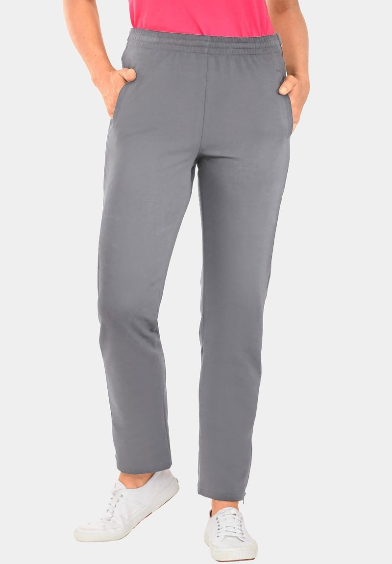 Grijze stretchbroek met een elastische tailleband, zijzakken en een taps toelopend ontwerp, gecombineerd met witte sneakers.