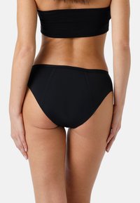 Parte inferiore di bikini nera con un design a taglio alto, texture liscia e cuciture minime. Presenta una parte posteriore a vita media e bordi senza cuciture.