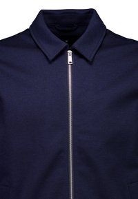 Veste à fermeture éclair bleu marine avec un col à revers, dotée d'une fermeture éclair argentée et d'un tissu texturé. Comprend une poche latérale sur le côté gauche inférieur.