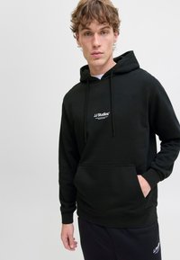 Zwarte hoodie met een voorzak, verstelbare koordjes en witte logo-details. Gemaakt van zachte stof en heeft een relaxte pasvorm.
