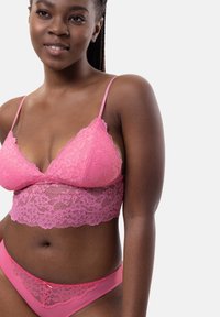Roze kanten bralette met een bloemmotief, voorzien van verstelbare bandjes en een brede kanten band. Bijpassende low-rise slipjes met kantaccenten.