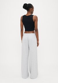 Μαύρο cropped τοπ χωρίς μανίκια συνδυασμένο με ανοιχτό γκρι φόρμα με φαρδιά μπατζάκια. Ομαλή υφή, casual σχεδίαση με ελαστική μέση.