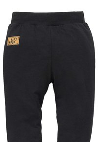 Pantaloni tuta neri realizzati in misto cotone, con vita a costine e una patch rettangolare "LET'S ROCK" in beige sul retro.